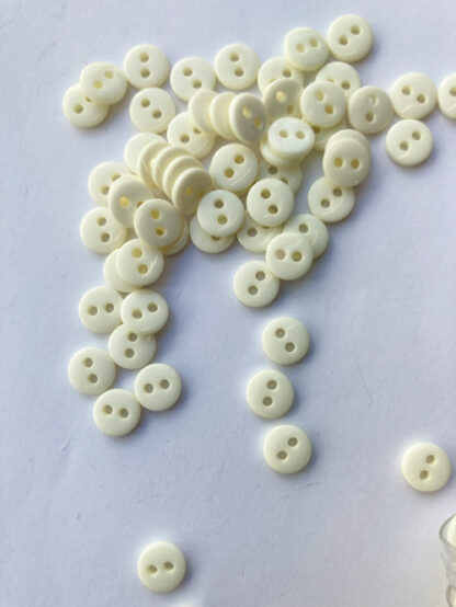 Cream two hole glossy extra small plastic button.