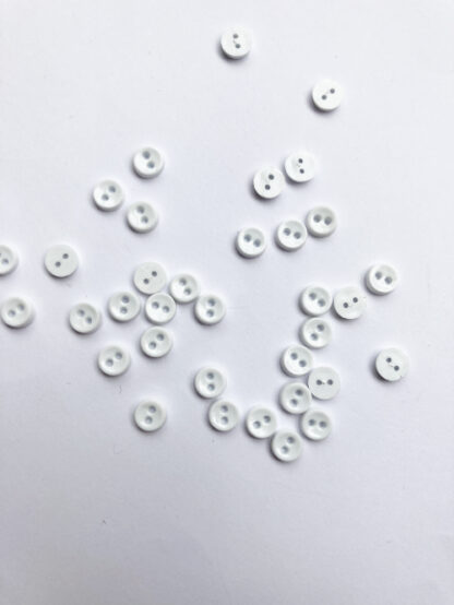 white miniscule 2 hole plastic button